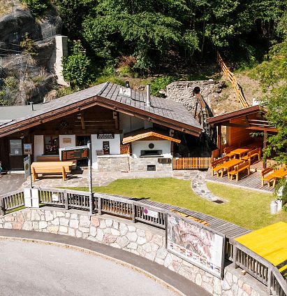 The traditional STampfle mill in Jerzens, surrounded by trees and rocks. Wooden benches have been set up in front of the building, creating a cosy outdoor area.
