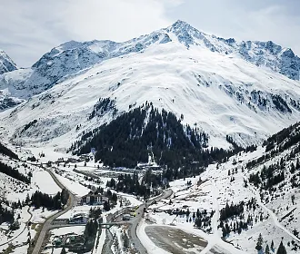 Luftbild vom Ort Mittelberg am Fuße des Pitztaler Gletschers mit dem dahinter liegenden Gipfel des Mittagskogels.