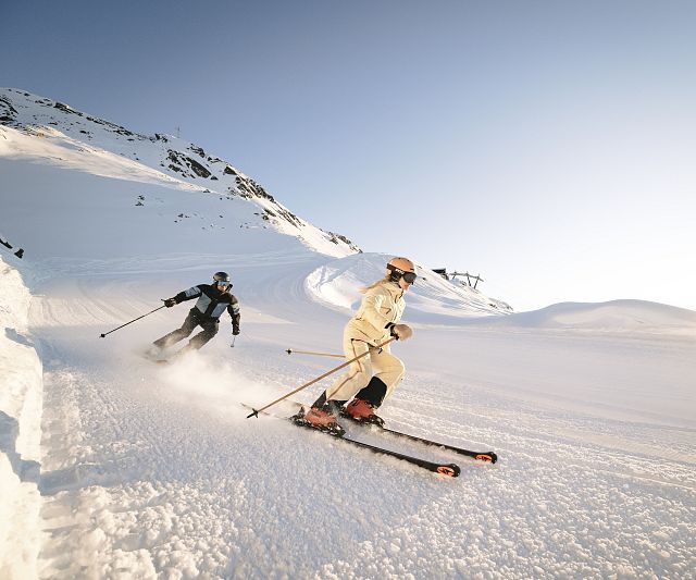 Zwei Skifahrer bei der Abfahrt im Sonnenuntergang im Skigebiet Hochzeiger