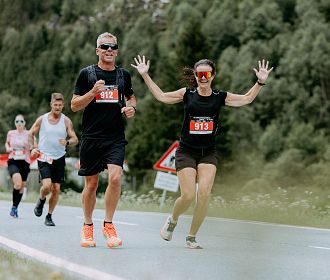 Halbmarathonläufer beim Gletschermarathon. Eine Läuferin jubelt mit den Händen in der Luft.