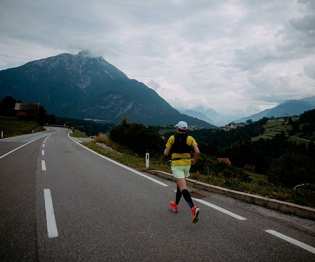 Ein Läufer des Gletschermarathons läuft auf der Straße in Richtung Arzl. Im Hintergrund ist der Tschirgant zu sehen.