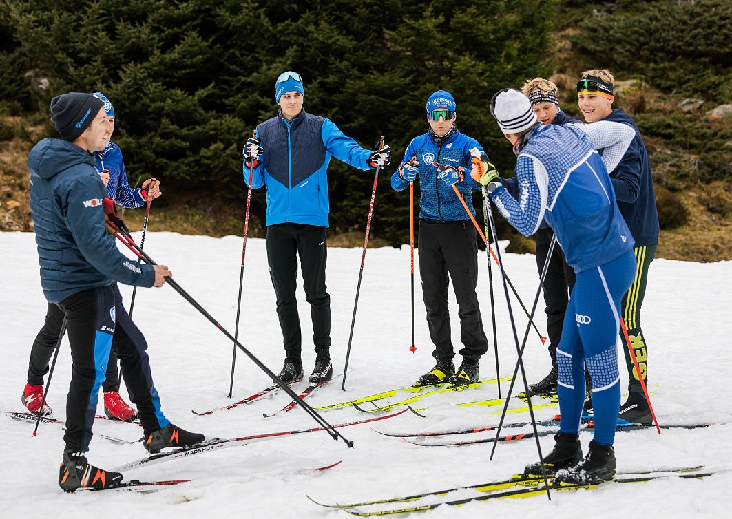 Gruppe von Langläufern im Pitztal auf schneebedecktem Boden, umgeben von Bäumen. Sportliche Kleidung, Skier und Stöcke, Winterfreizeit, Naturerlebnis, Teamgeist.