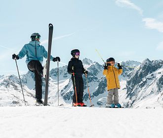 Familie bei Sonnenschein beim Skifahren im Skigebiet Hochzeiger