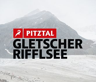 Eine Landschaft mit einem Gletscher und einem klaren See im Vordergrund. Im Hintergrund erhebt sich ein hoher Berg, umgeben von grauem Himmel und Nebel.