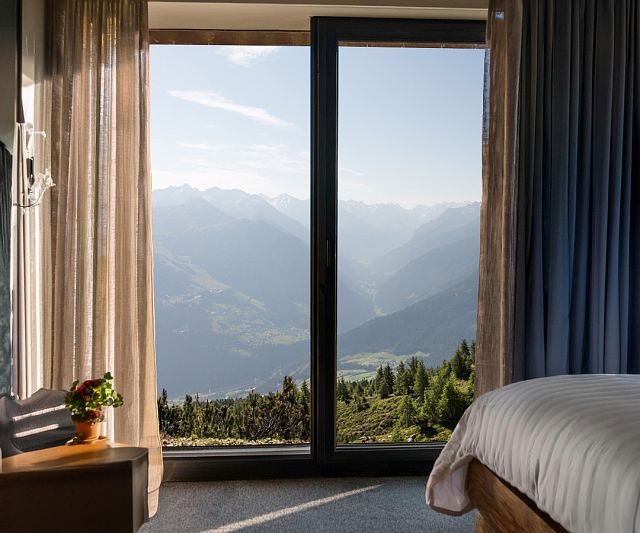 Hotelzimmer von innen mit einem sommerlichen Ausblick auf die Berge