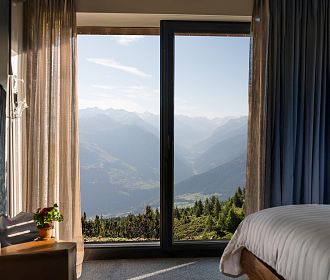 Hotelzimmer von innen mit einem sommerlichen Ausblick auf die Berge