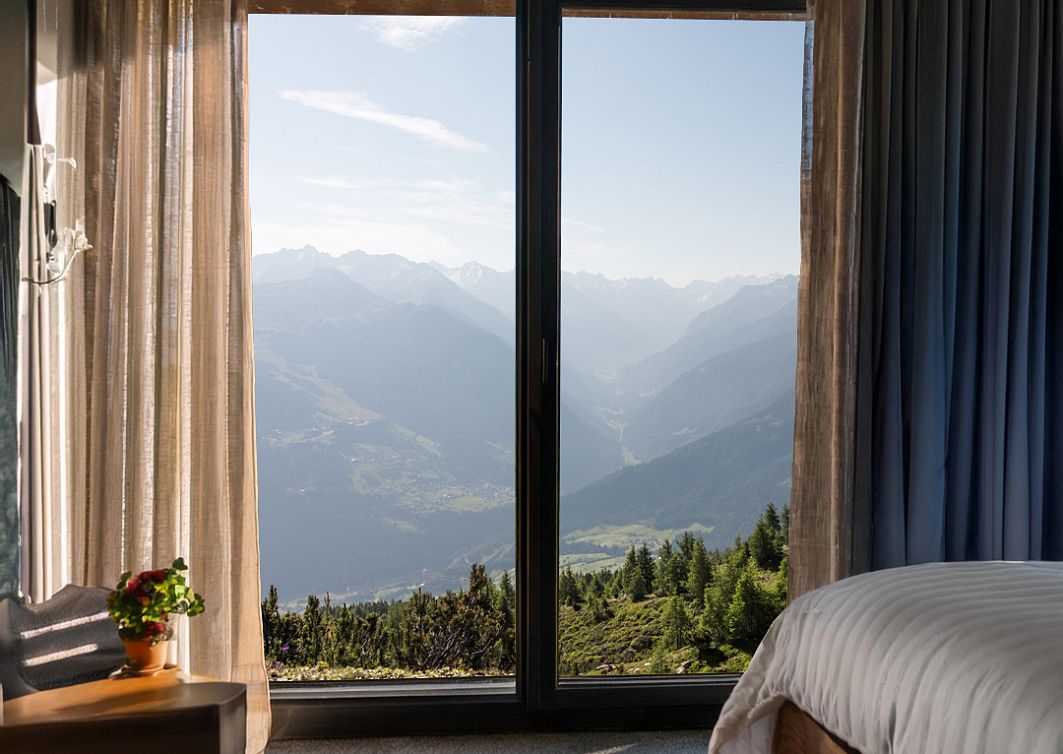 Hotelzimmer von innen mit einem sommerlichen Ausblick auf die Berge