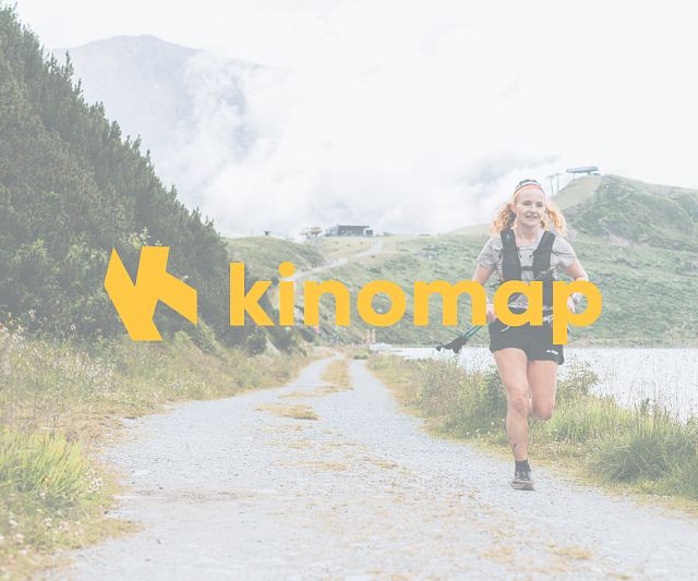 Eine Frau joggt auf einem schmalen Weg entlang eines Gewässers, umgeben von grüner Natur und Bergen. Im Vordergrund ist das Logo von Kinomap sichtbar.