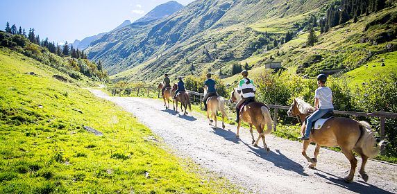 Eine Gruppe an Reitern inmitten der malerischen Landschaft des Pitztals im Sommerurlaub in Tirol.