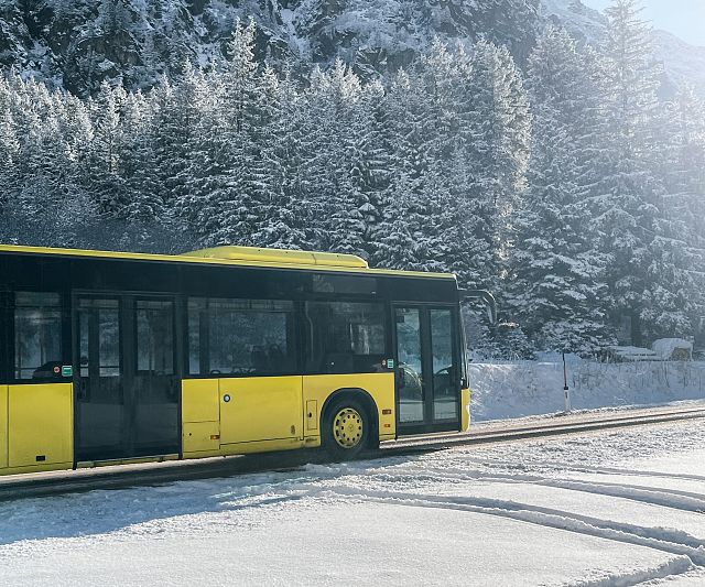 Ein gelber Bus fährt durch eine verschneite Winterlandschaft
