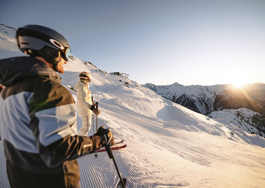 Zei Skifahrer genießen den Sonnenuntergang auf der Piste im Skigebiet Hochzeiger